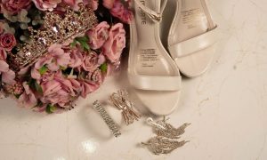 A flat lay of quinceañera accessories including shoes, tiara, and flowers on a marble surface. — Ab Rocket Advantages and Sho