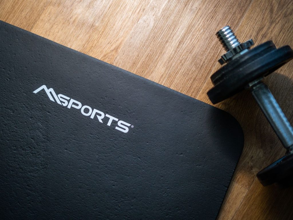 Flat lay of a gym mat and dumbbell on wooden floor, ideal for indoor workouts. — Essential Elements About Gravity Edge Dwelli