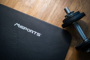 Flat lay of a gym mat and dumbbell on wooden floor, ideal for indoor workouts. — Essential Elements About Gravity Edge Dwelli