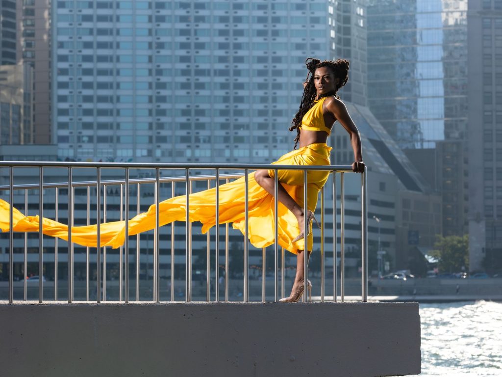 Stunning fashion model in flowing yellow dress with Chicago skyline backdrop. — Horizon Work out Bikes Evaluation