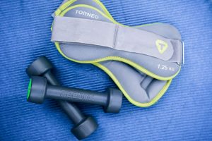 From above of modern dumbbells and leg weight belts placed on blue fitness mat in studio — Weider Skilled 5500 Multi Well bei